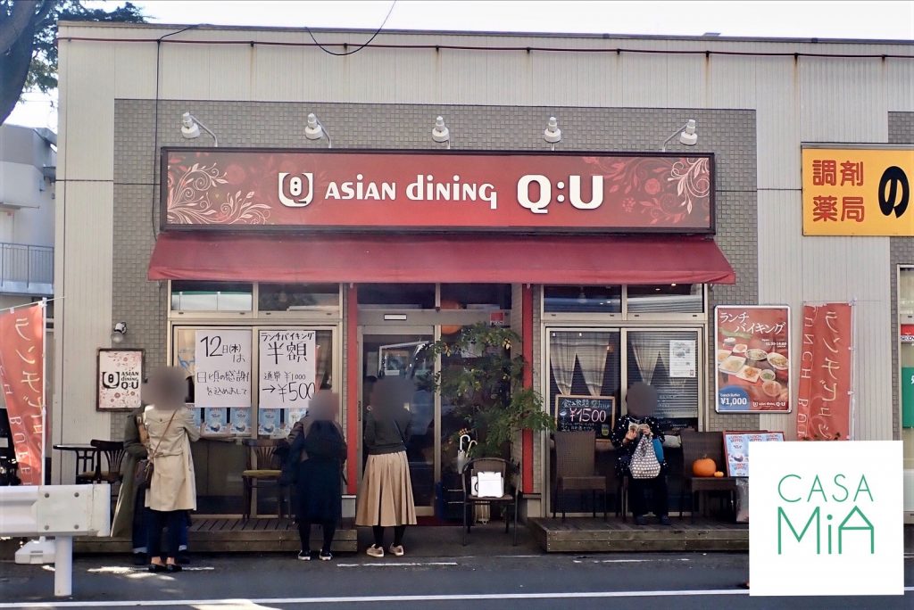 赤い建物のアジアン料理レストランとその前に並ぶたくさんのお客さん